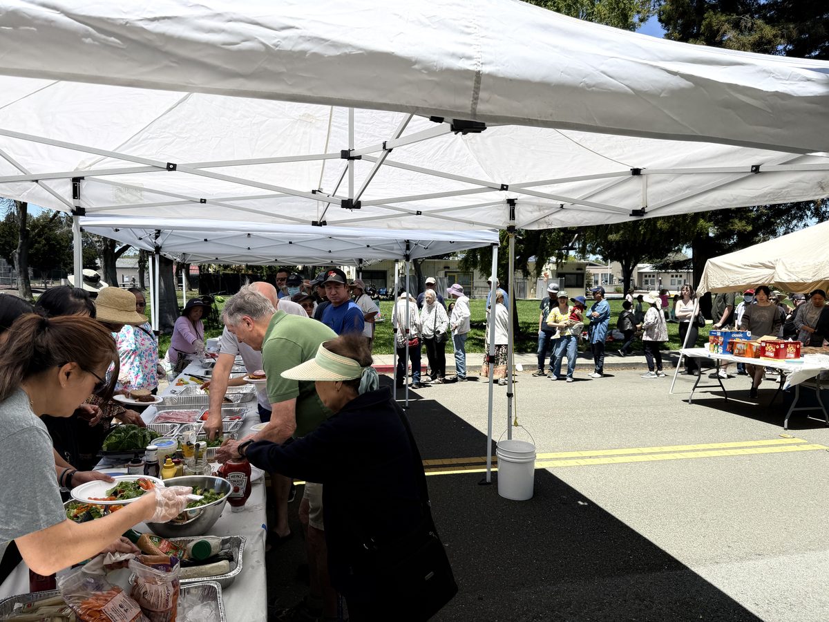 Neighbors lining up for food under the canopies on San Pierre Street